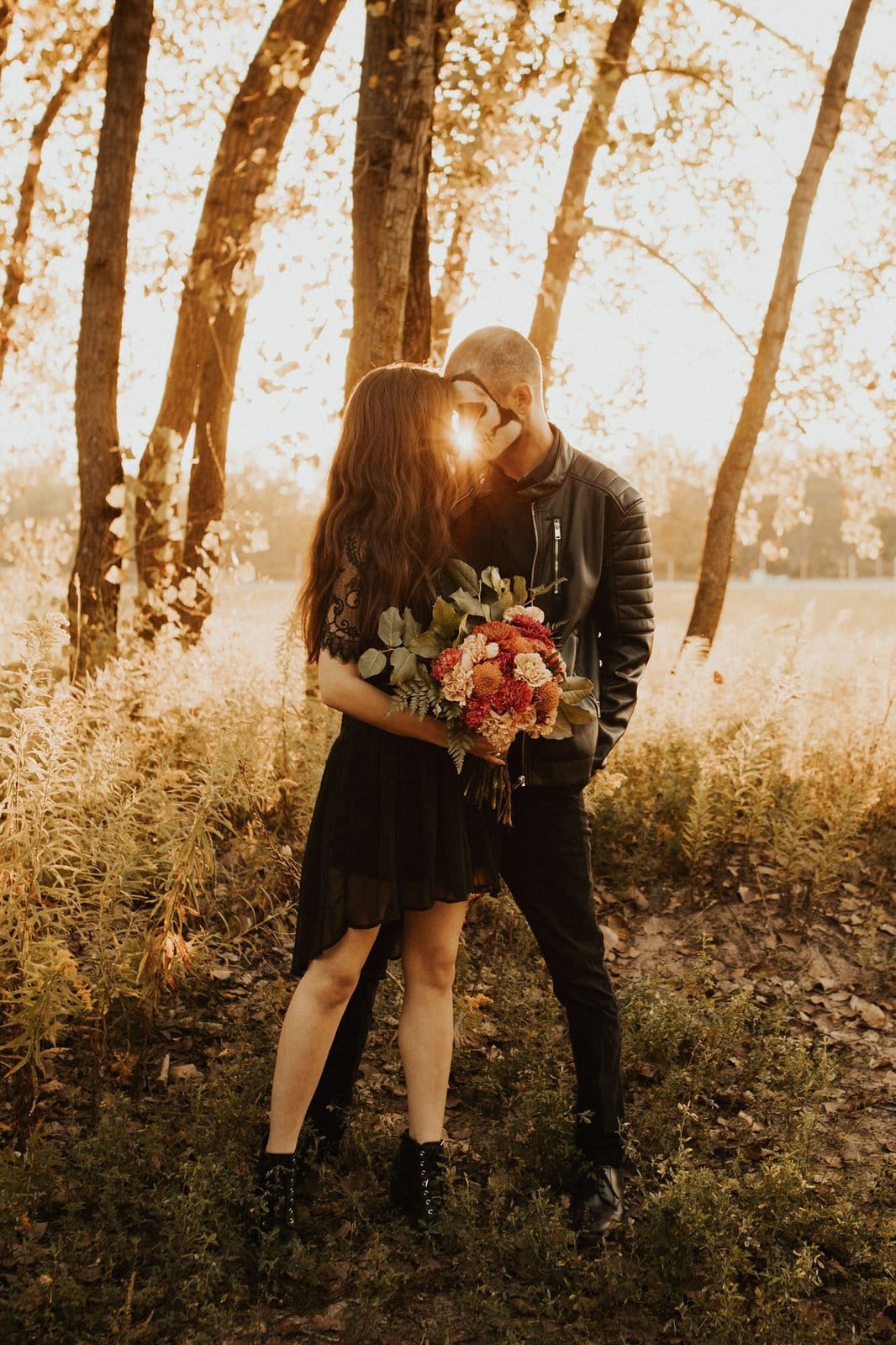 halloween couple embrace in woods.