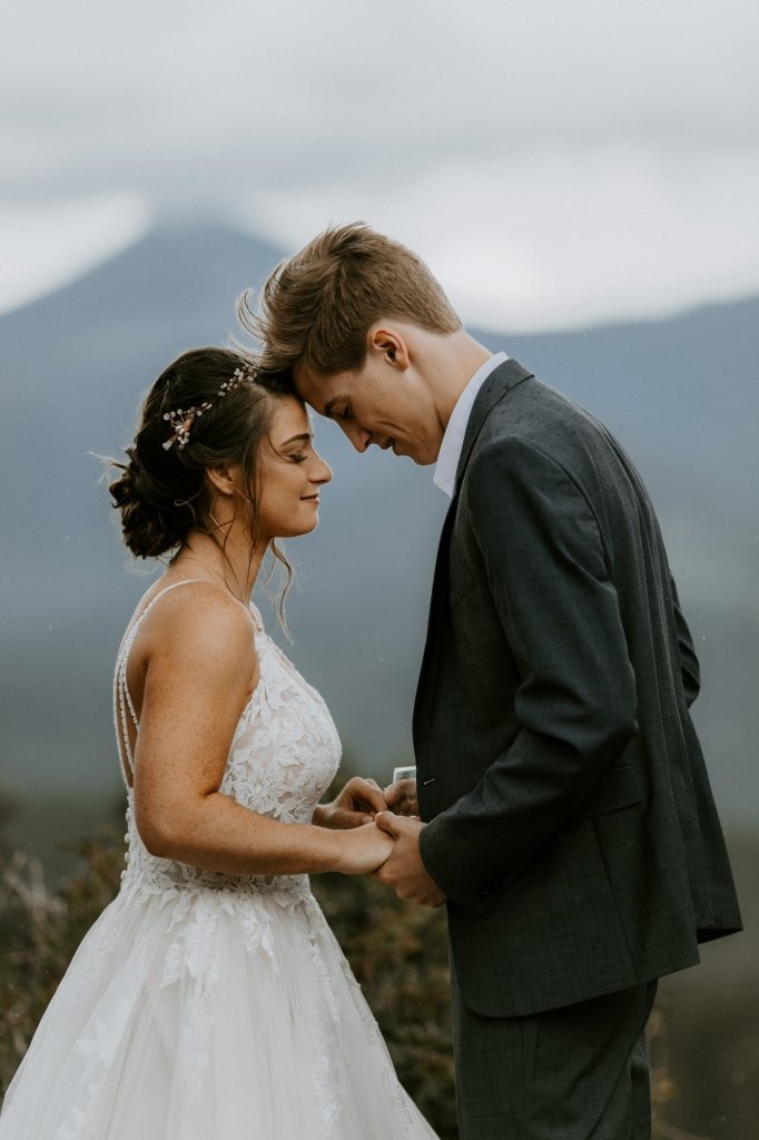 Bride and groom pray during rocky mountain wedding.