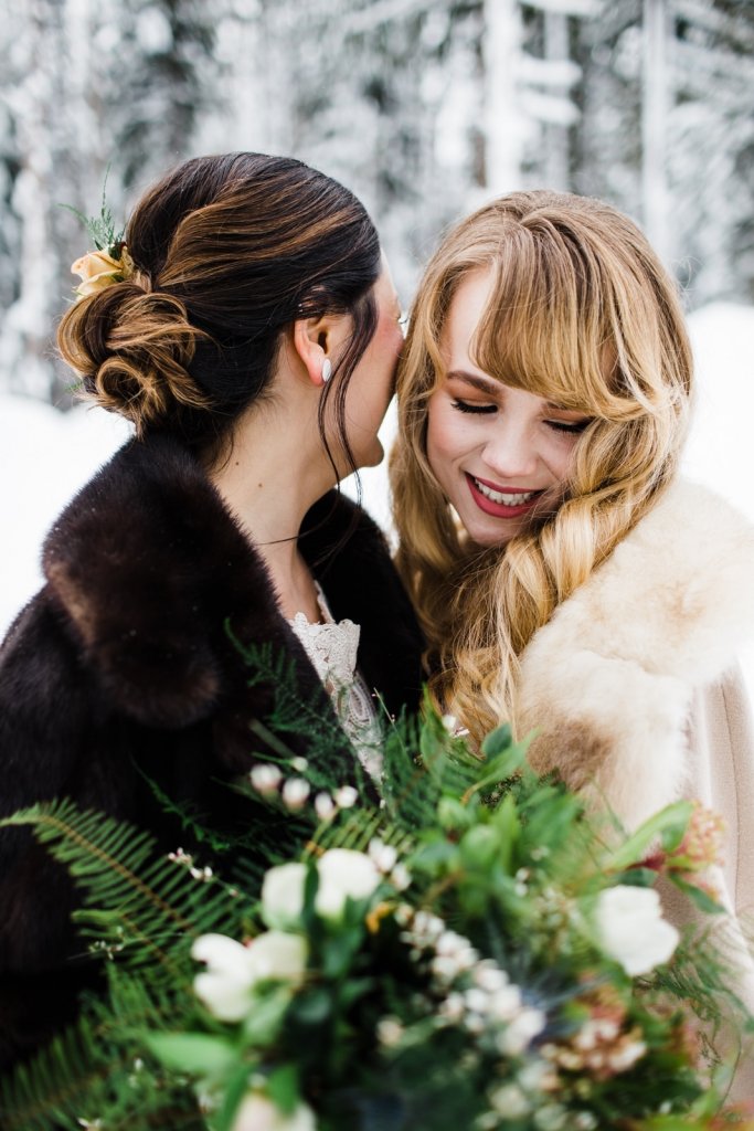 brides snuggle during winter wedding portraits.