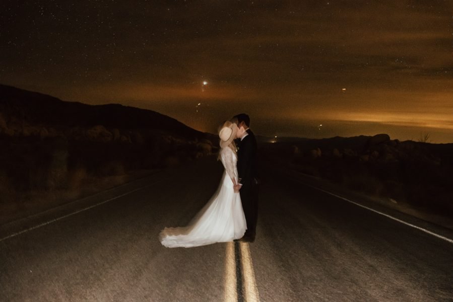 Couple stands in the street kissing at night under the stars