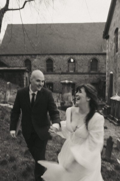 Couple running through a historic churchyard in Providence. Photo by Rhode Tripper Photography.