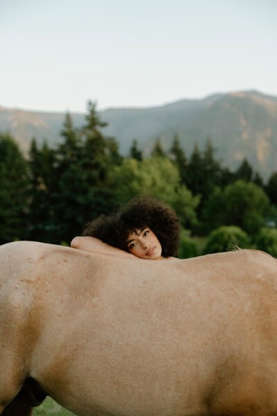 A couple stands in a field with a horse at sunset for their Oregon elopement photos.