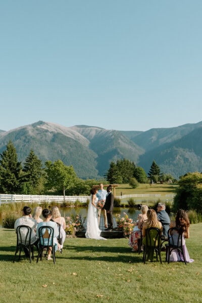 A couple stands in front of mountains during their Oregon elopement ceremony.