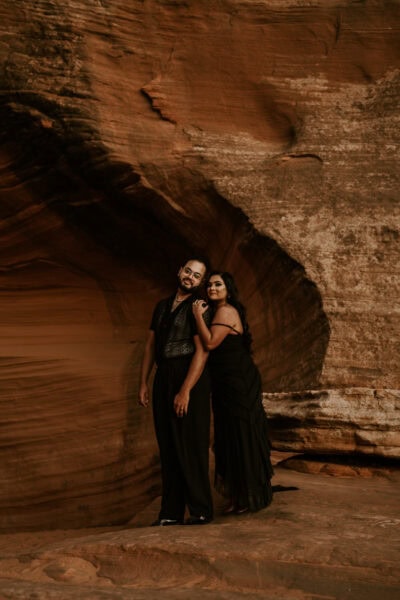 Against the backdrop of red desert cliffs and a setting sun, the couple in black elopes in the heart of nature’s grandeur.