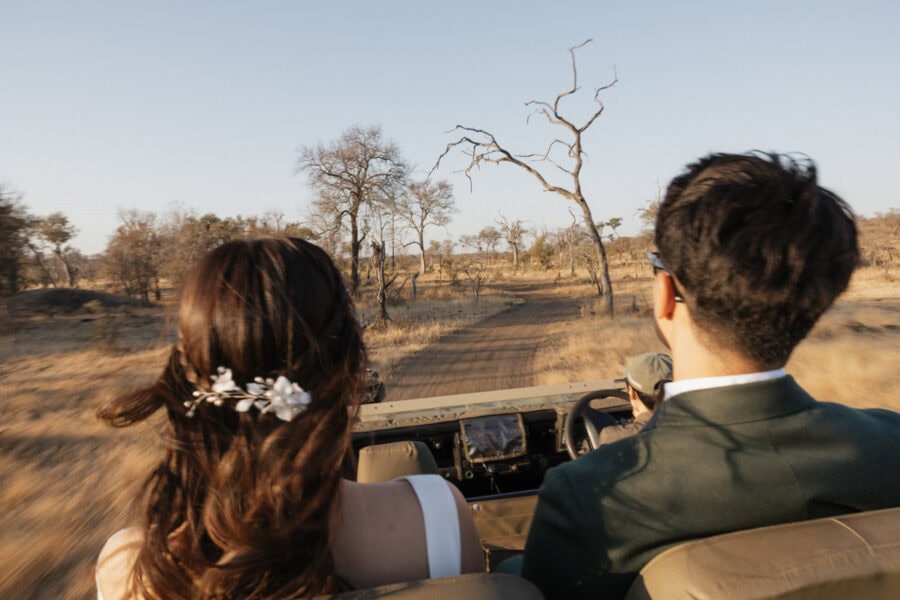 Bride and groom driving on game viewer during their safari elopement in South Africa.