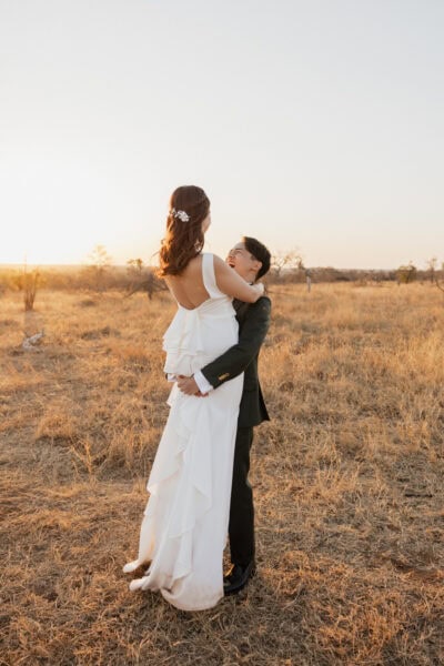 Groom lifts and spins bride while bathed in golden afternoon light.