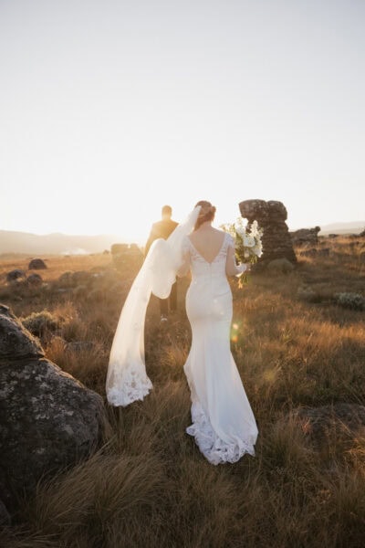 Bride and groom walk through rocky outcrop on Escarpment during helicopter elopement in the Blyde Canyon Region of South Africa.
