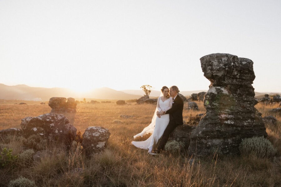 Bride and groom embrace amongst rocky outcrop on Blyde Canyon Escarpment during helicopter elopement in Hoedspruit